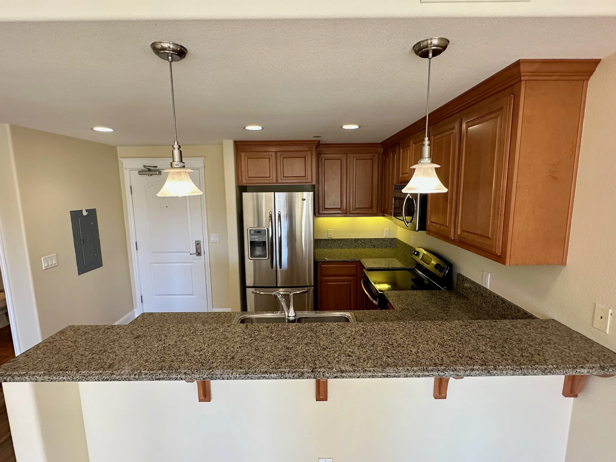 Modern kitchen with granite peninsula countertop and pendant lighting in luxury Gilroy apartment at Monterey Terrace